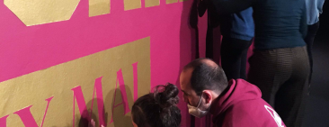 Persones amb ulls tencats toquen els vinils informatius a la paret de l'exposició