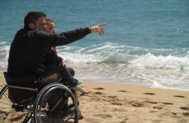 Un pare que va en cadira de rodes a la platja amb el seu fill