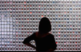 cabecera Exposición El sueño, mujer de espaldas viendo fotografías de pequeño formato