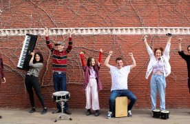 Banda de musica levantan los brazos alegres enseñando sus instrumentos