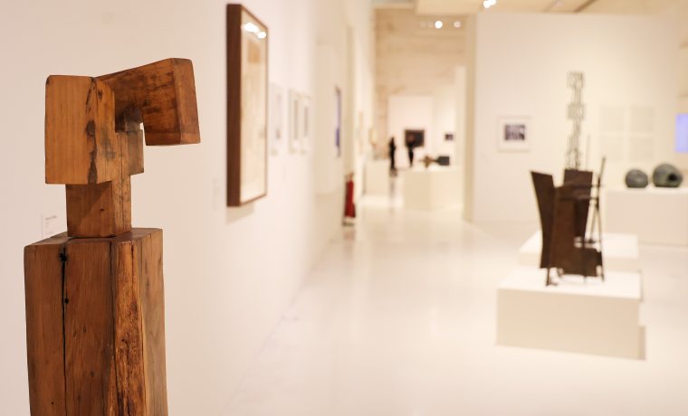 Erakusketa aretoko argazkia. Lehen planoan Chillidaren egurrezko eskultura bat ikusten da eta bigarren planoan altzairuzko beste bat.