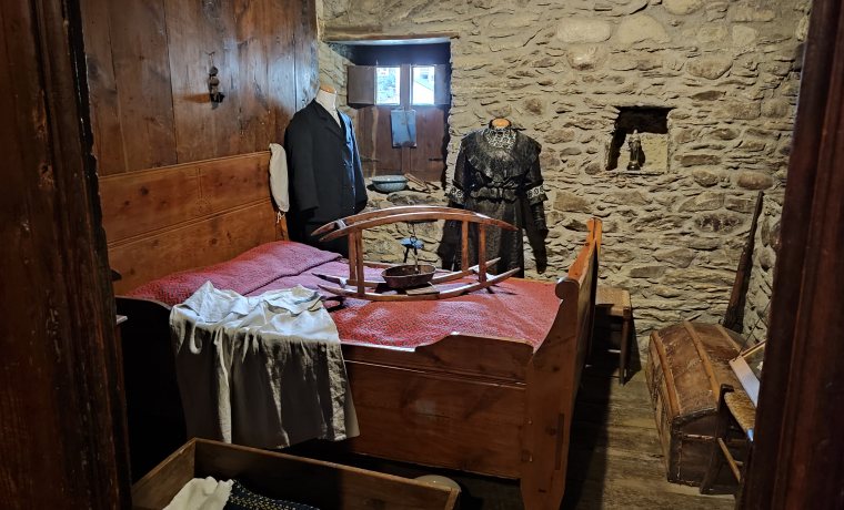 Habitació de matrimoni de Casa Gassia amb el llit, l'escalfallits, el bressol i diverses peces de roba