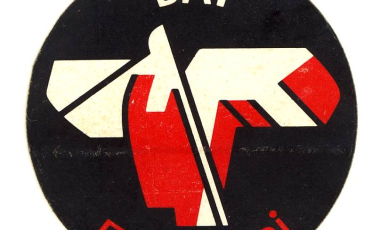 Pegatina de fondo negro con el texto "Bai euskarari" en blanco y rojo y una figura geométrica central en rojo y blanco