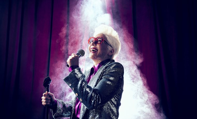 Dona amb micròfon il·luminada per un focus zenital amb un teló de fons