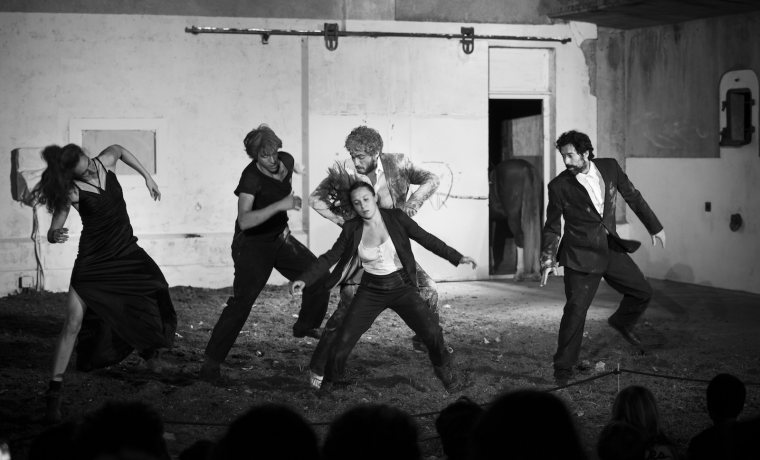 Fotografia en blanc i negre. Surten diverses persones ballant sobre un terra que sembla terra. 